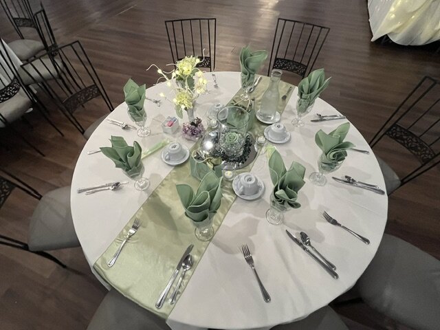 Reception table set with green linens and seasonal centerpiece