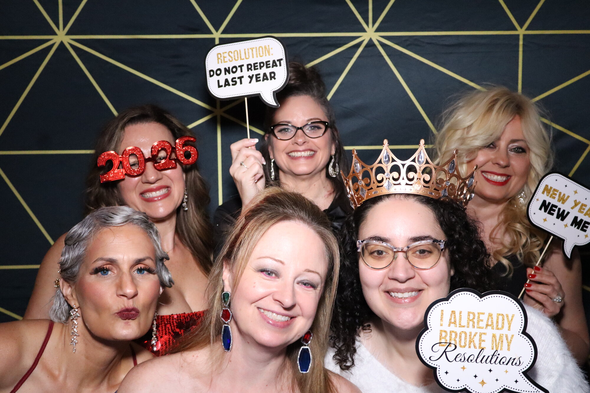 Friends pose at the Maravela's NYE Gala photo booth with 2026 props, gold geometric backdrop behind them
