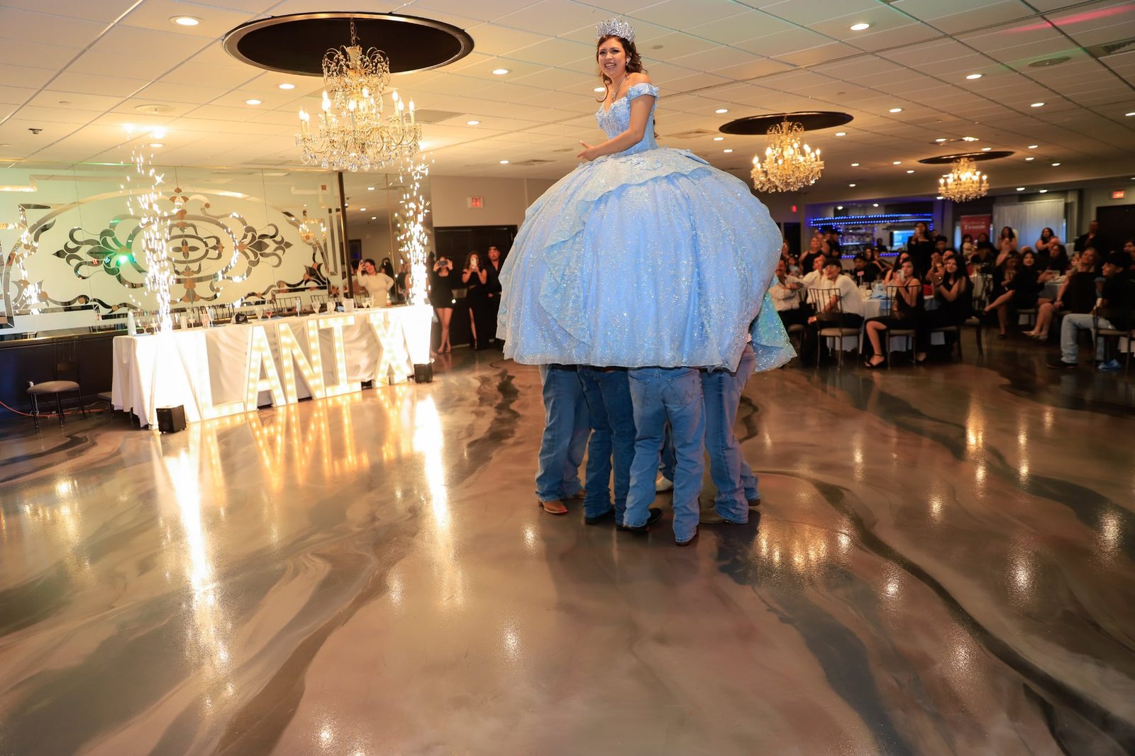The quinceañera dances with her court beneath the chandeliers at Maravela's