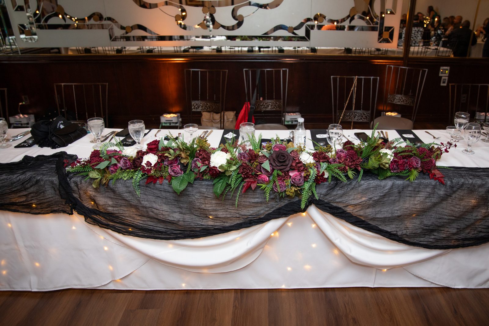 The head table dressed with burgundy florals for a wedding reception at Maravela's